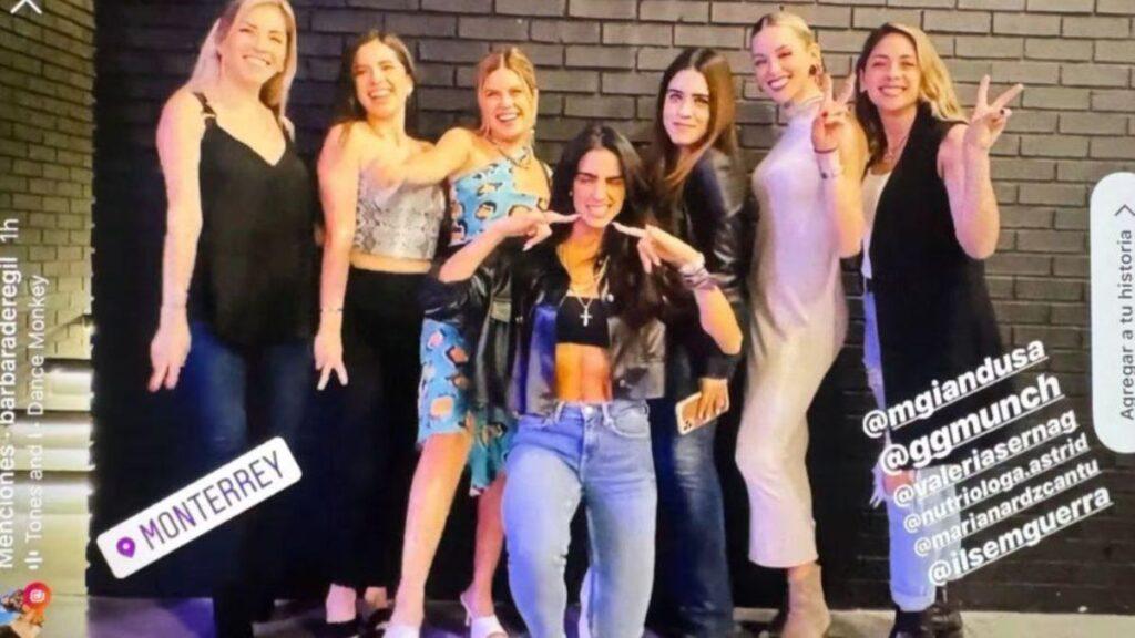 Eight Young Women Pose Together Against a Brick Wall, Smiling at the Camera; Center Figure Wears a Crop Top and Leather Jacket Making Finger Guns. Monterrey Tag Visible on the Image. | La Silla Regia