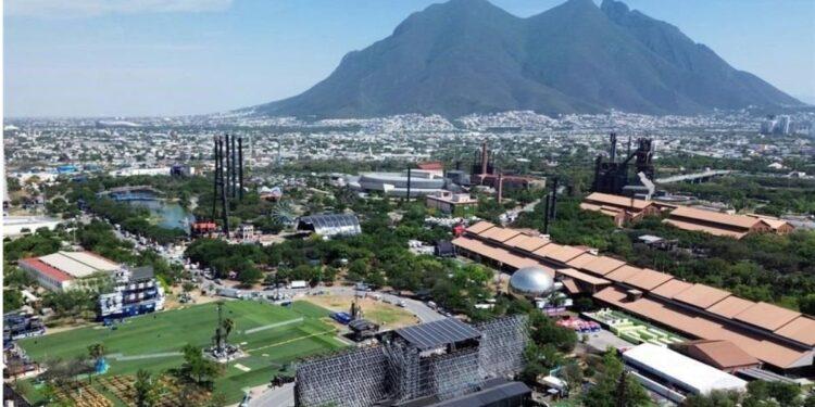 Aerial View of a City with a Large Sports Field, Festival Grounds, and Industrial Structures, Set Against a Mountain Backdrop. | La Silla Regia