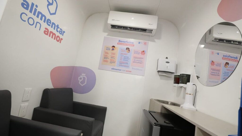 Small Clinic Waiting Area with Two Black Armchairs, Wall Decal Reading 'alimentar Con Amor', and a Wall Poster Under a Mounted Air Conditioner. | La Silla Regia