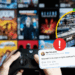 Person Holds a Game Controller in the Foreground; a Collage of App Covers Blurs Behind, with a Circular Inset of a Stock Exchange Trading Floor Highlighted in Yellow and an Alert Badge, Plus a Bluesky Tweet About Microsoft. | La Silla Regia